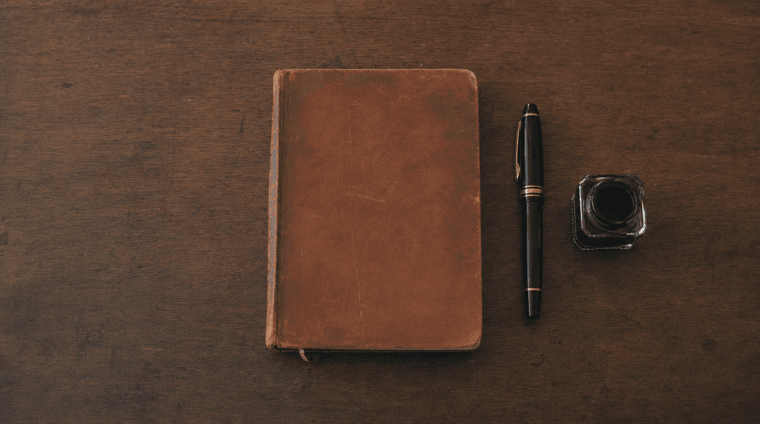 Cahier ouvert sur une table en bois clair, papier crème, ambiance feutrée — aucune main, aucun téléphone