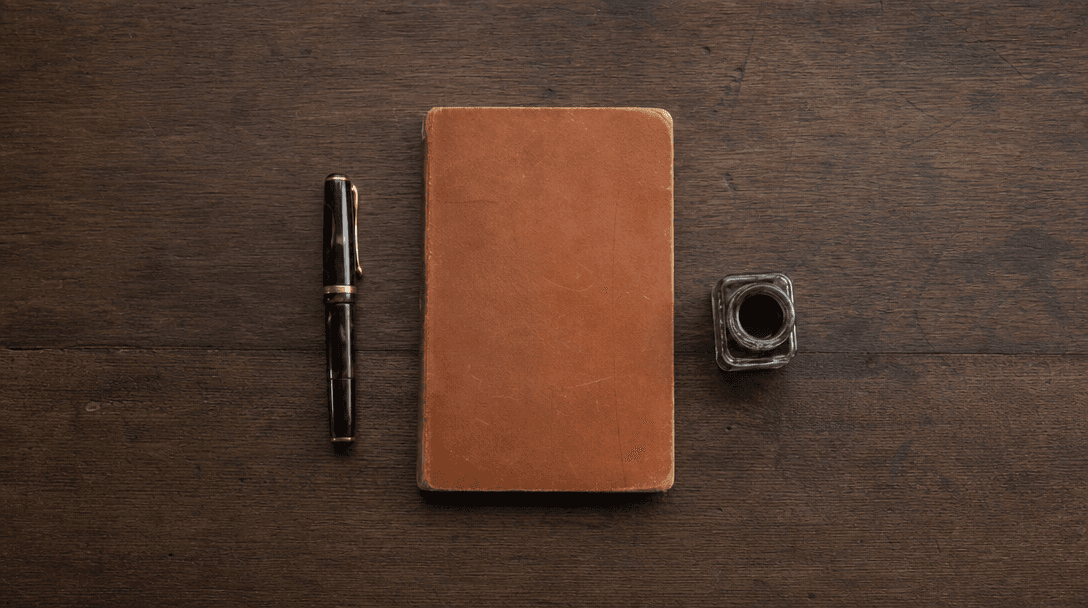Cahier ouvert sur une table en bois clair, papier crème, ambiance feutrée